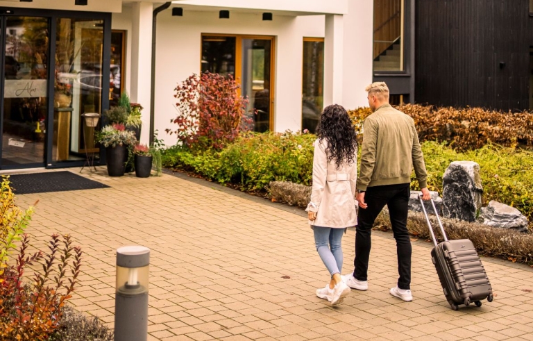 Ein Paar mit Gepäck betritt ein modernes Hotel.