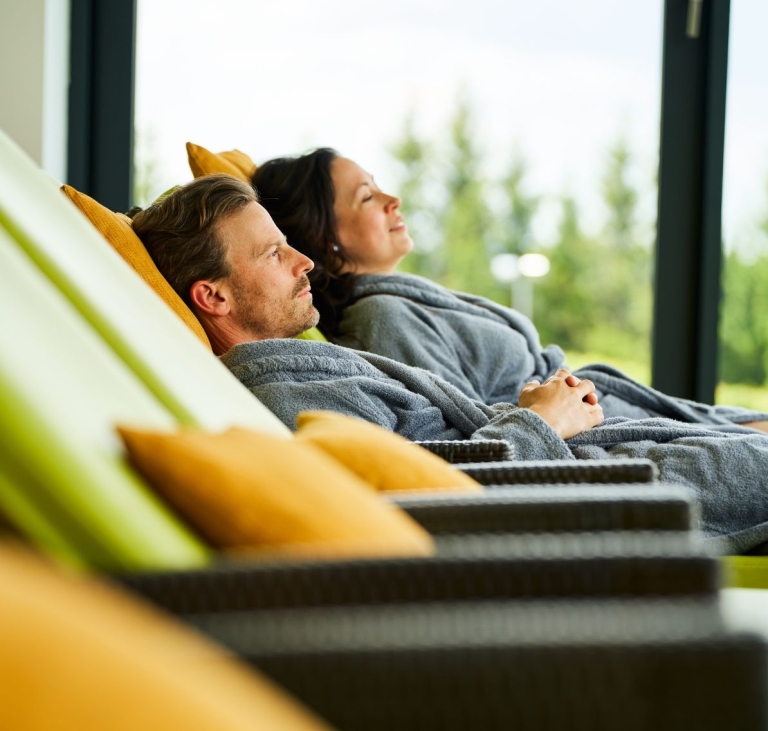 Paar entspannt in einem Wellnessbereich in Bademänteln